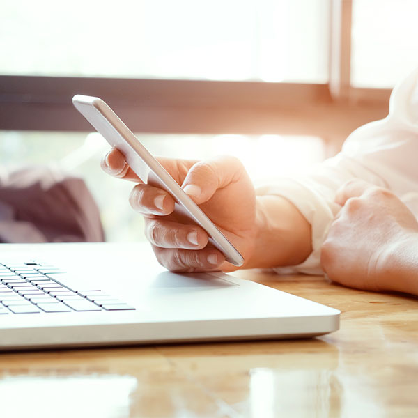 Businessman using laptop and mobile phone.